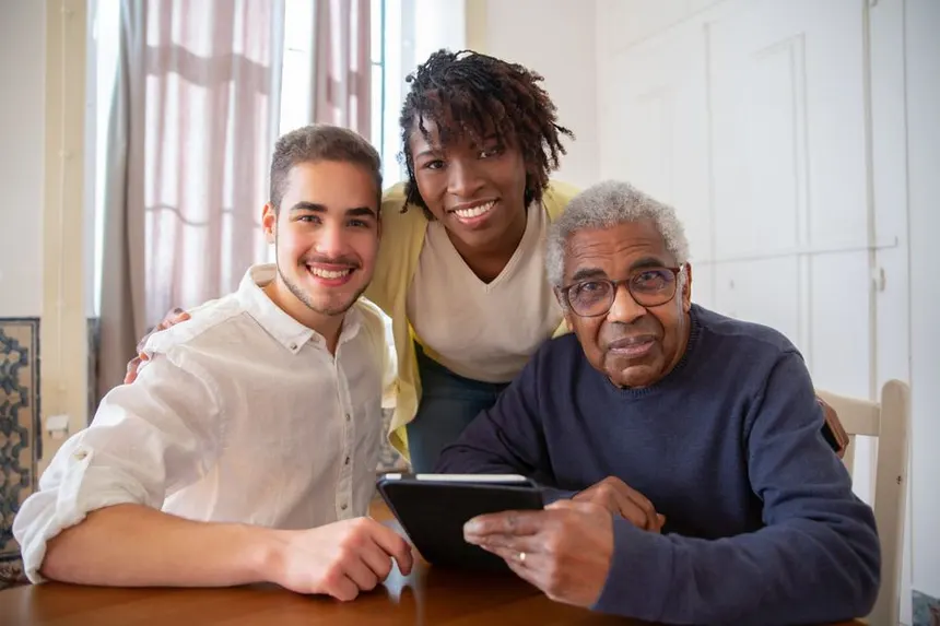 Older adult using a tablet with two younger family members, staying mentally engaged